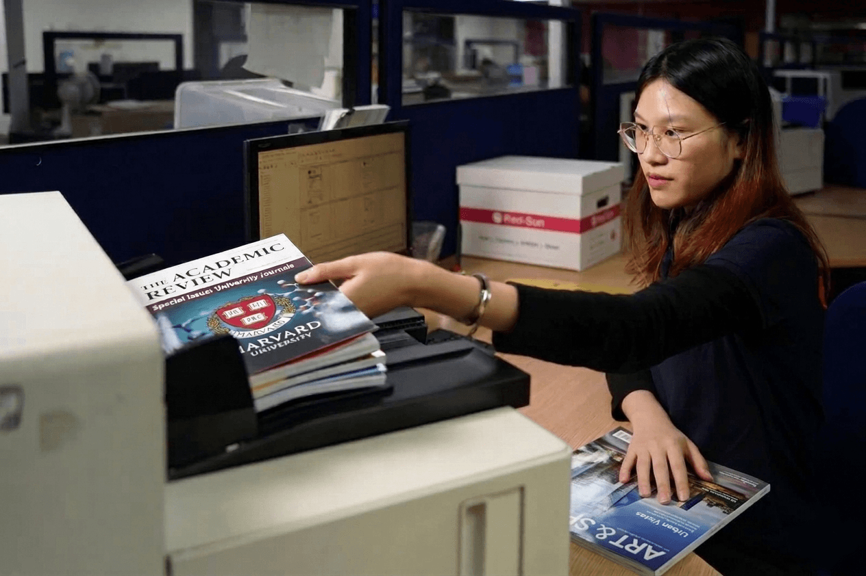 Scanning personnel digitising magazines and post processing images using scanners and imaging applications in a scanning bureau environment.